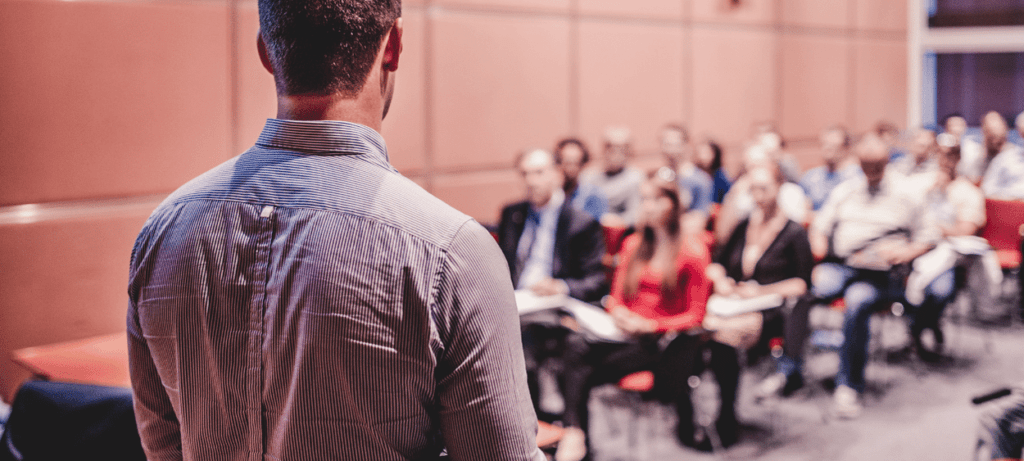 Prezentující pán před plnou posluchárnou lidí