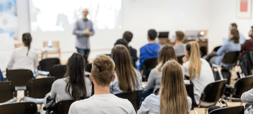 Plná posluchárna lidí a u tabule přednášející