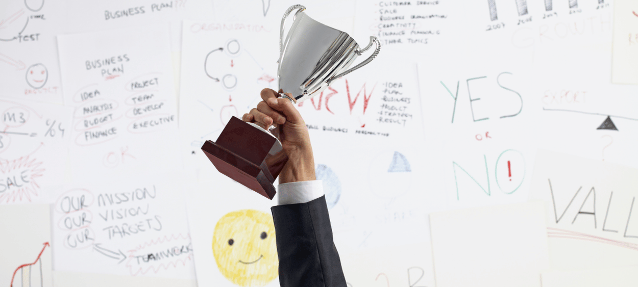 Ruka držící pohár před tabulí