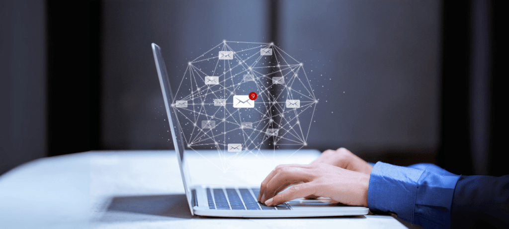 Na obrázku je notebook ze strany, nad ním levituje emailingová síť