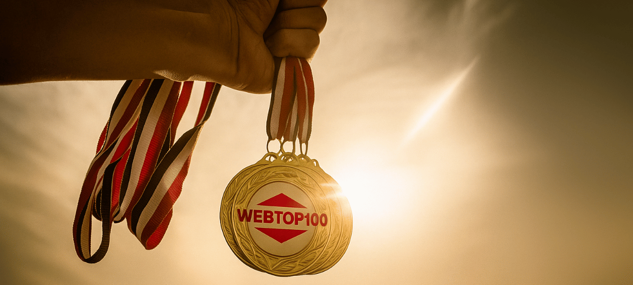 Na obrázku je ruka držící medaile na kterých je logo webtop100