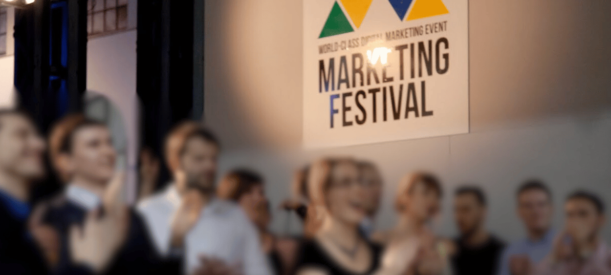 fotka z marketing festivalu 2015 - fotka ze zaměřená na logo festivalu na zdi a před ním jde dav lidí, kteří jsou na fotce trošku rozmazaní, protože jsou v pohybu.